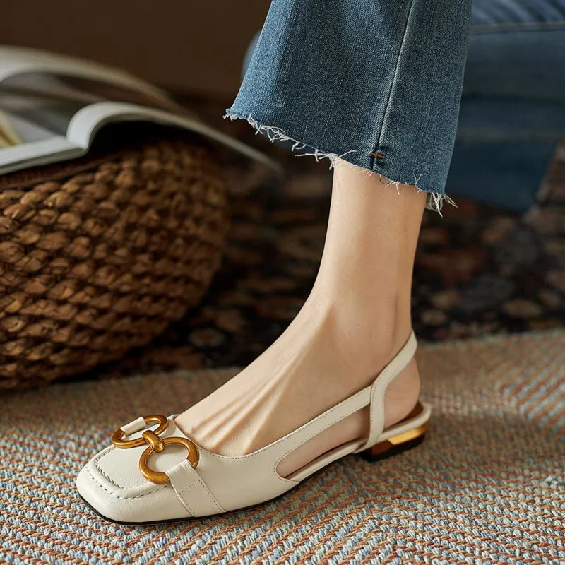 White flat shoe with gold buckle on a blurred background